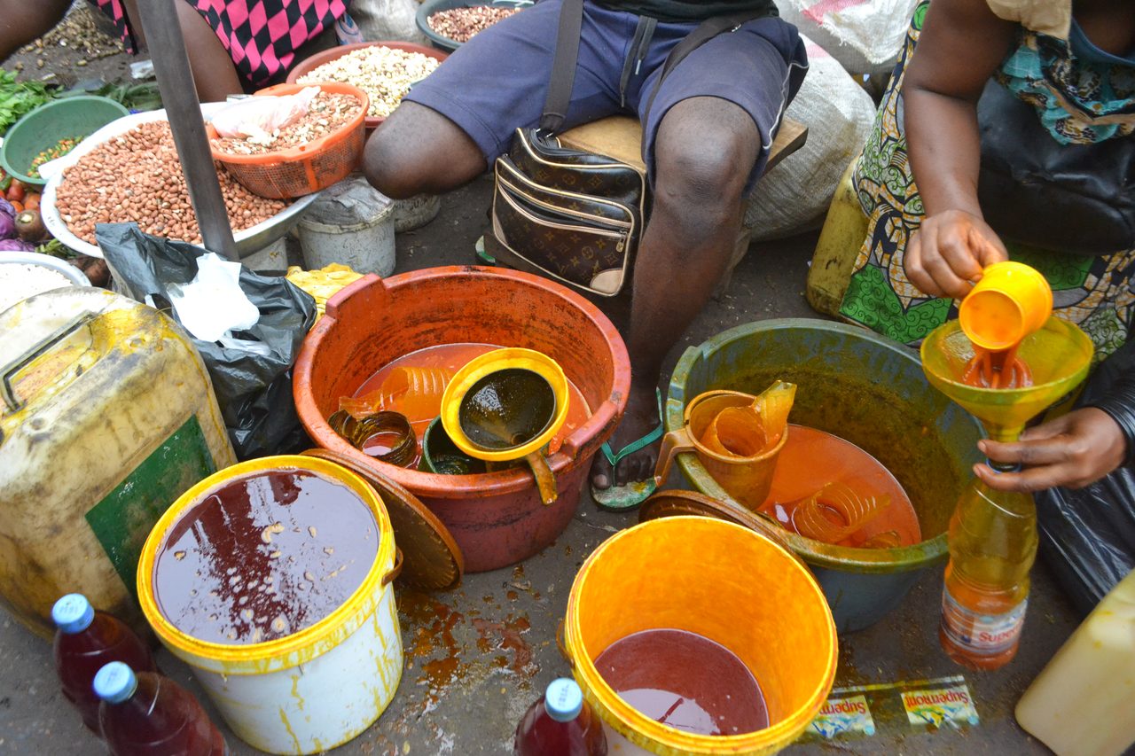 Bidons d'huile de palme rouge vendus sur un marché ouest-africain