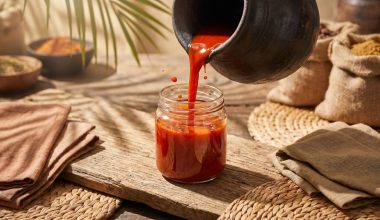 Huile de palme rouge versée d'un pot en terre dans un bocal en verre